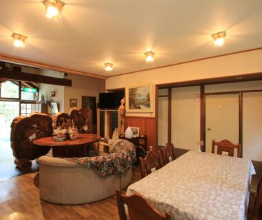 Ryokan communal lounge with wooden furniture, sofa, low table, sliding doors at Minshuku Hiroshige in Oita