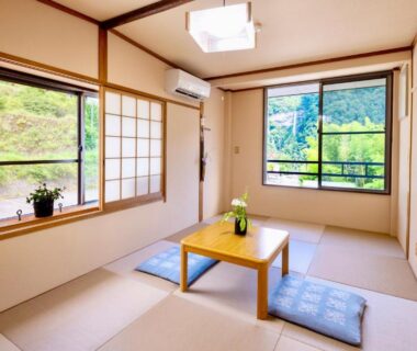 Bright tatami room with low table, cushions, shoji screens and green mountain view in Wakayama