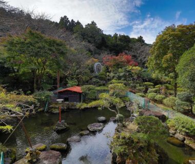 Japanese garden pond with stepping stones, pavilion and landscaped greenery at Ichinose ryokan in Shizuoka