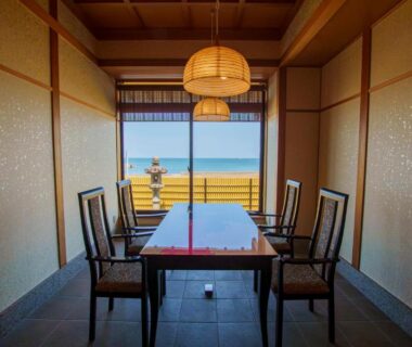 Dining room with table, shoji screens and balcony overlooking ocean at Senshin Waho, Hyōgo, Kansai