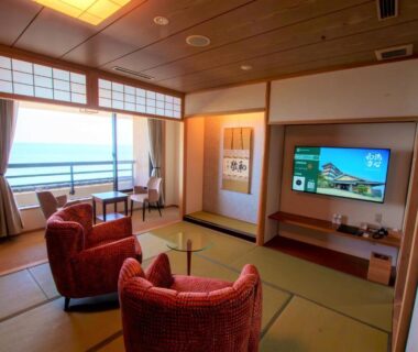 Tatami room with red armchairs, low table, shoji screens and balcony overlooking the sea at Senshin Waho, Hyōgo