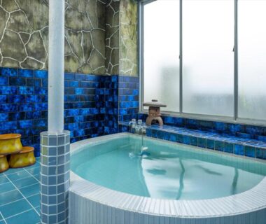 Indoor blue tiled onsen tub with wooden stools and frosted windows at Marubun Dorogawa Onsen