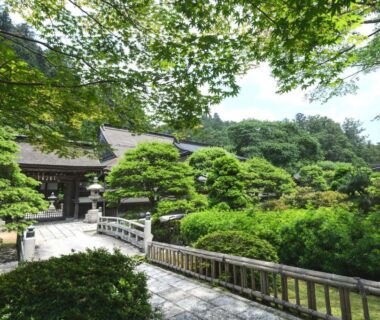 Traditional ryokan entrance with wooden bridge and manicured Japanese garden at 清浄心院 in Wakayama