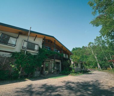 Two-story ryokan exterior with gravel forecourt and surrounding trees at Sansō Watari, Nagano, Chūbu, Japan
