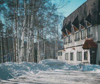 Snow-covered facade with balconies and birch trees at Sansō Watari, Nagano