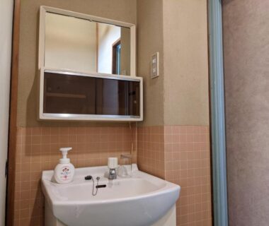 Small washbasin with mirror and soap dispenser at Onsenya Hirosuke, Fukushima