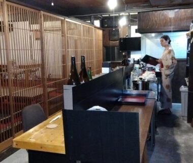 Wooden counter and latticed dining area with staff in kimono at Onsenya Hirosuke, Fukushima