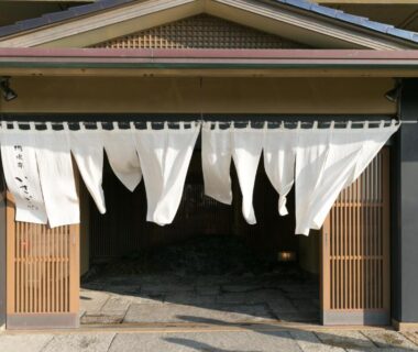 White noren curtains and wooden sliding doors at Yūsuitei Isagoya entrance in Yamagata
