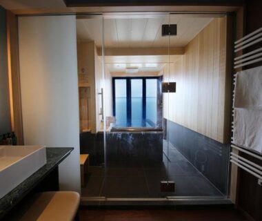 Indoor soaking tub with glass partition, vanity and towel rack at Yūsuitei Isagoya, Yamagata