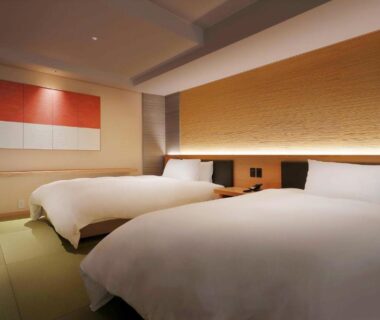 Twin beds on tatami flooring with soft lighting and modern Japanese decor at Yūsuitei Isagoya, Yamagata