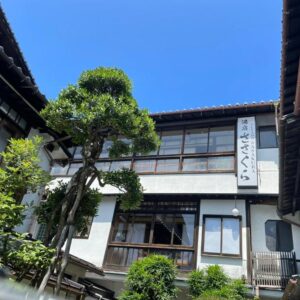 Traditional multi-story ryokan exterior with wooden balconies, shoji windows and courtyard tree at Yuyado Sasakura, Hyōgo