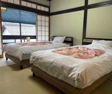 Tatami-floored room with two single beds, shoji screens and small seating by window at Yuyado Sasakura, Hyōgo