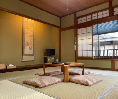 Traditional tatami room with low wooden table, floor cushions, shoji screens and hanging scroll at Yuyado Sasakura in Hyōgo
