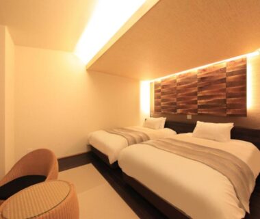 Two single beds with warm lighting and low chairs at Yuyado Miyuki in Gunma, Kantō