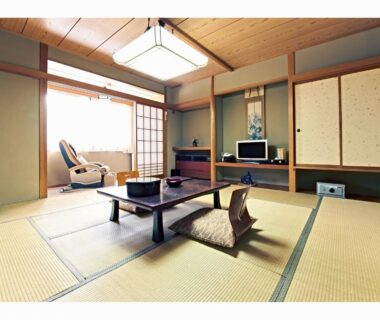 Traditional tatami room with low table, zabuton cushions, shoji screens and TV at Yuyado Miyuki in Gunma