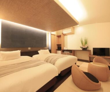 Twin beds with low seating, warm indirect lighting and TV in a modern ryokan room at Yuyado Miyuki, Gunma