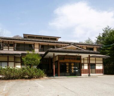 Front entrance of Yushō Fukujikan with wooden facade, covered canopy and surrounding trees in Gifu, Chūbu region