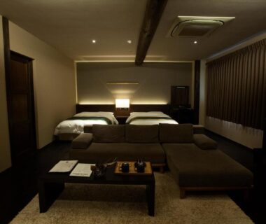 Relaxing twin bedroom with low wooden table, chaise lounge and bedside lamps at Oyado Kotobuki, Yumura Onsen, Hyōgo