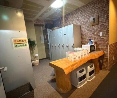 Changing area with metal lockers and central wooden bench against exposed brick at Auberge de poudreuse de Yuzawa, Niigata