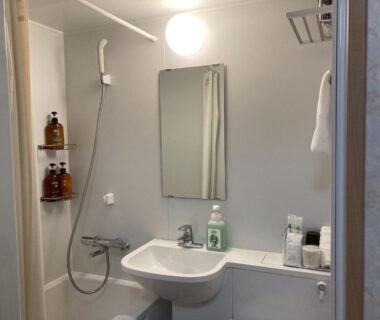Small shower bathroom with sink, mirror and toiletries at Auberge de poudreuse de Yuzawa Niigata