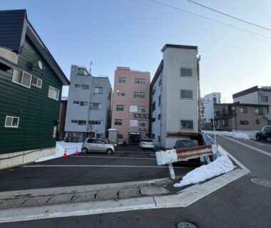 Street view of Auberge de poudreuse de Yuzawa with buildings, parking and small snow patches in Niigata