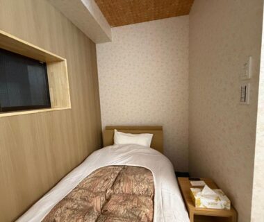 Single bed with patterned comforter in compact wood-paneled room at Auberge de poudreuse de Yuzawa, Niigata, Chūbu