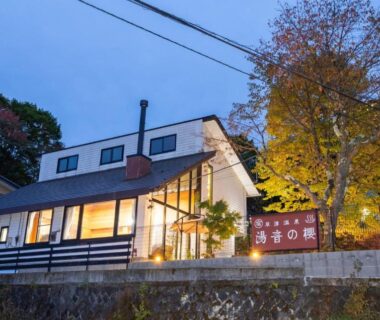 Ryokan exterior at dusk with lit windows and signboard for Yune no Sakura in Gunma, Kantō