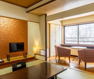 Tatami room with low table, seating by window and wooded view at Fukunoya in Gunma