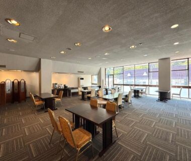 Bright lounge with tables, chairs, carpeted floor and large windows at Fukunoya in Gunma, Kantō