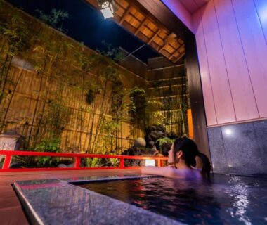 Guest soaking in wooden onsen bath beside bamboo wall in courtyard at Ryokan Hōetsu, Atami, Shizuoka