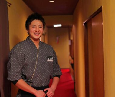 Attendant in traditional yukata smiling in a ryokan corridor at Ryokan Hōetsu, Atami, Shizuoka, Chūbu