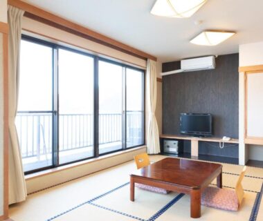 Sunlit tatami room with low table and sliding balcony doors at Yunoyado Hiratsuru, Shizuoka