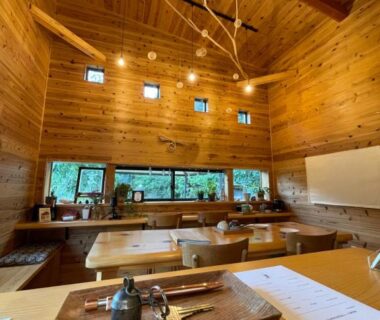High-ceiling wooden dining interior with counter seating, trays and utensils, large window overlooking greenery at 玄か~sizuka~ Kyoto