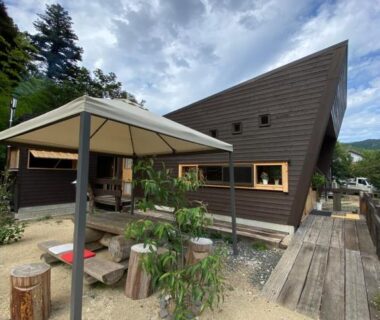 Gravel courtyard with canopy seating beside a dark wooden ryokan building in Kyoto mountains