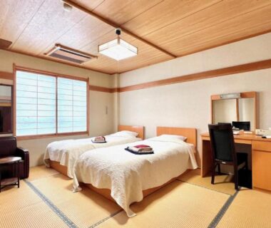 Tatami-floored twin room with two beds, shoji window, wooden ceiling and desk at Keyaki no Yado in Yamagata