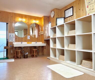 Wood-paneled changing room with cubby shelves, baskets and sinks at Keyaki no Yado in Yamagata