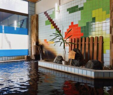 Tiled indoor onsen pool with mosaic wall and wooden accents at Keyaki no Yado, Yamagata