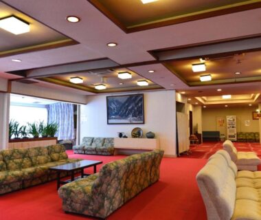 Upholstered sofas and low tables on red carpet in Keyaki no Yado lobby, Yamagata