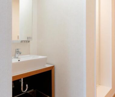 Compact washbasin and mirror with wooden shelving at Mizu no Yado Asakusa, Tokyo