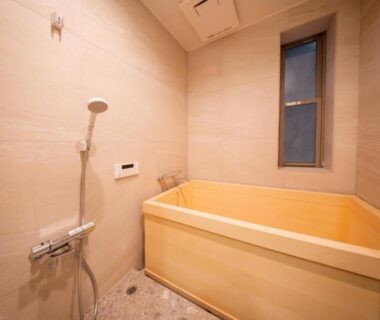 Indoor wooden soaking tub with handheld shower and tiled walls at Mizu no Yado Asakusa Tokyo