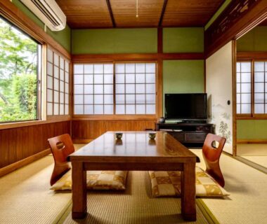 Traditional tatami room with low wooden table, zabuton cushions and shoji screens at Ryoso Makibanoie in Ōita, Kyushu