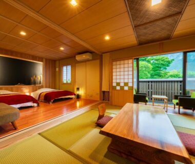 Spacious Japanese room with tatami, low wooden table, raised twin beds and shoji doors opening to balcony with lush greenery