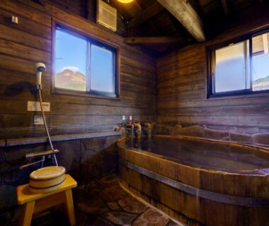 Indoor wooden soaking tub with stool and hand shower at Ryoso Makibanoie in Ōita, Kyūshū