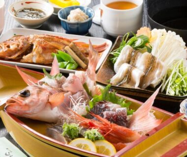 Boat-shaped platter with whole fish, prawns, lemon and garnishes surrounded by small side dishes