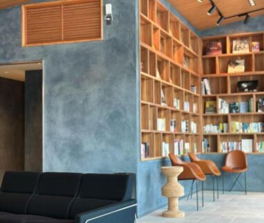 Contemporary lounge with bookshelf wall, black sofa and wooden chairs at Takenokura Sansō, Kumamoto, Kyūshū