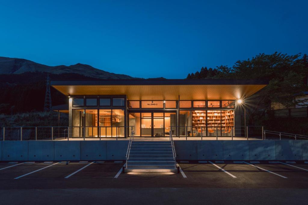 Evening ryokan entrance Takenokura Sansō Kumamoto Lit glass facade and steps at Takenokura Sansō with parking and mountain silhouette in Kumamoto, Kyūshū