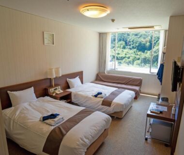 Twin beds with window seat and greenery outside, Kiimiso ryokan, Wakayama