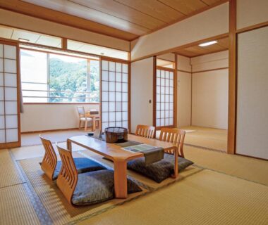Spacious tatami room with low table, floor cushions, shoji screens and garden-view window