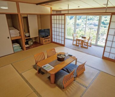 Tatami room with low table, zabuton chairs and stacked futons at Kiimiso, Wakayama, Kansai