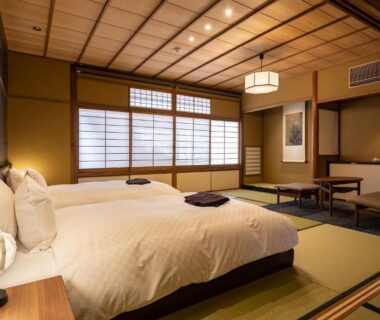 Tatami room with twin beds, shoji screens, low table and warm lighting at Kyōka auberge de Gion, Kyoto